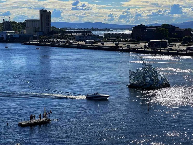 Oslo harbour with a modern sculpture in the water and boats sailing by.