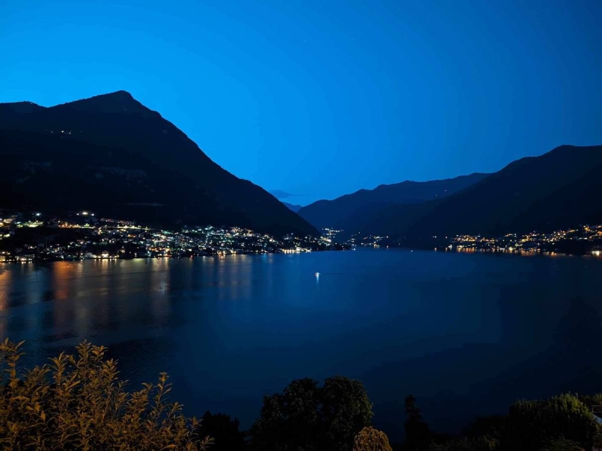 Λίμνη Κόμο στη blue hour το βράδυ, με φωτισμένα χωριά στην ακτή και αντανάκλαση των φώτων στο νερό, με φόντο τα βουνά.