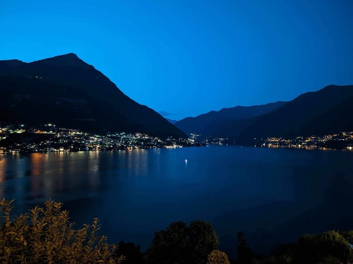 Λίμνη Κόμο στη blue hour το βράδυ, με φωτισμένα χωριά στην ακτή και αντανάκλαση των φώτων στο νερό, με φόντο τα βουνά.