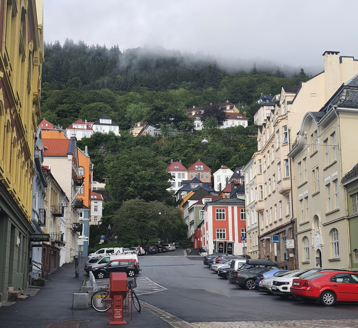 Γειτονιά στο Μπέργκεν με πολύχρωμα σπίτια που ανεβαίνουν στο βουνό και ομίχλη πάνω από τα δέντρα