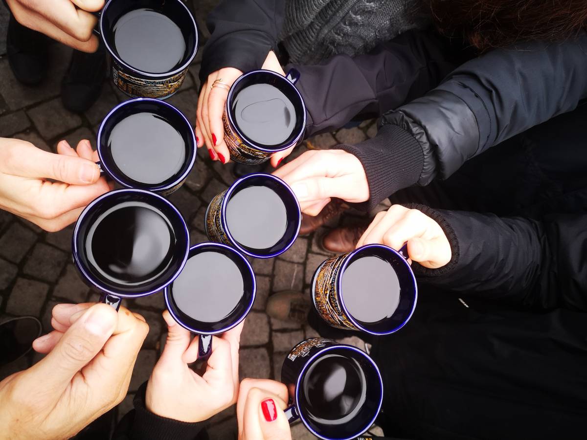 Κούπες με ζεστό κρασί (vin chaud) σε κύκλο — χέρια φίλων στις αγορές της Αλσατίας.