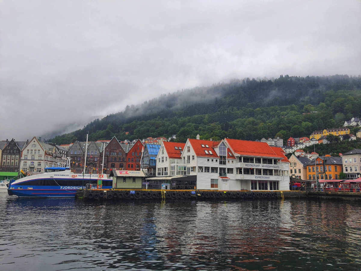 Σκάφος για fjord cruise στο λιμάνι του Μπέργκεν, με τα πολύχρωμα σπίτια και βουνά με ομίχλη στο φόντο
