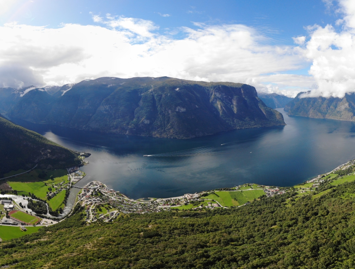 Θέα σε μεγάλο νορβηγικό φιόρδ με ψηλά βουνά και μικρό χωριό στις όχθες, ιδανική εκδρομή από το Μπέργκεν