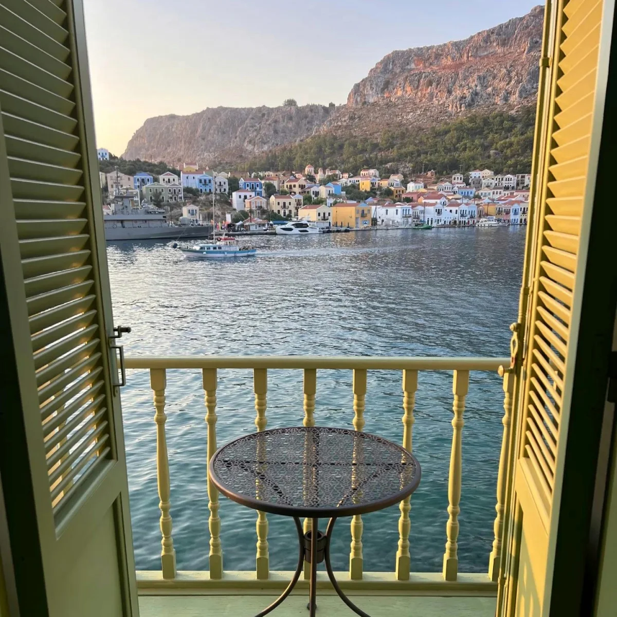 Open window looking out over the sea and a quiet seaside village on a travel morning.