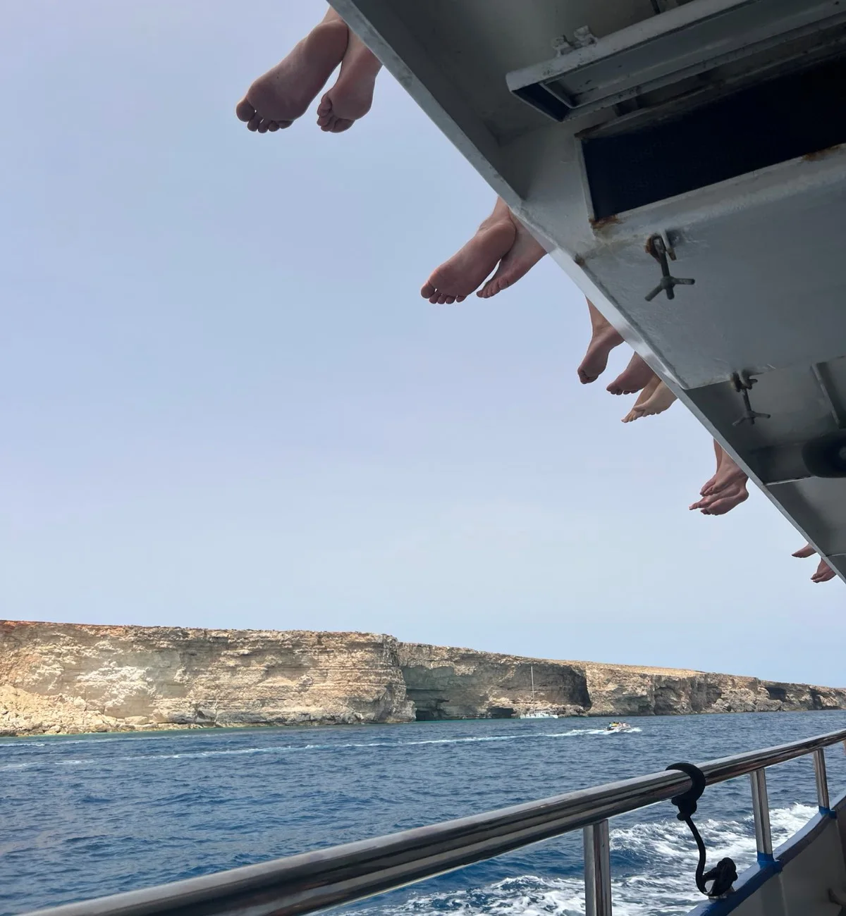 Feet dangling off a boat over the sea on a spontaneous summer day.